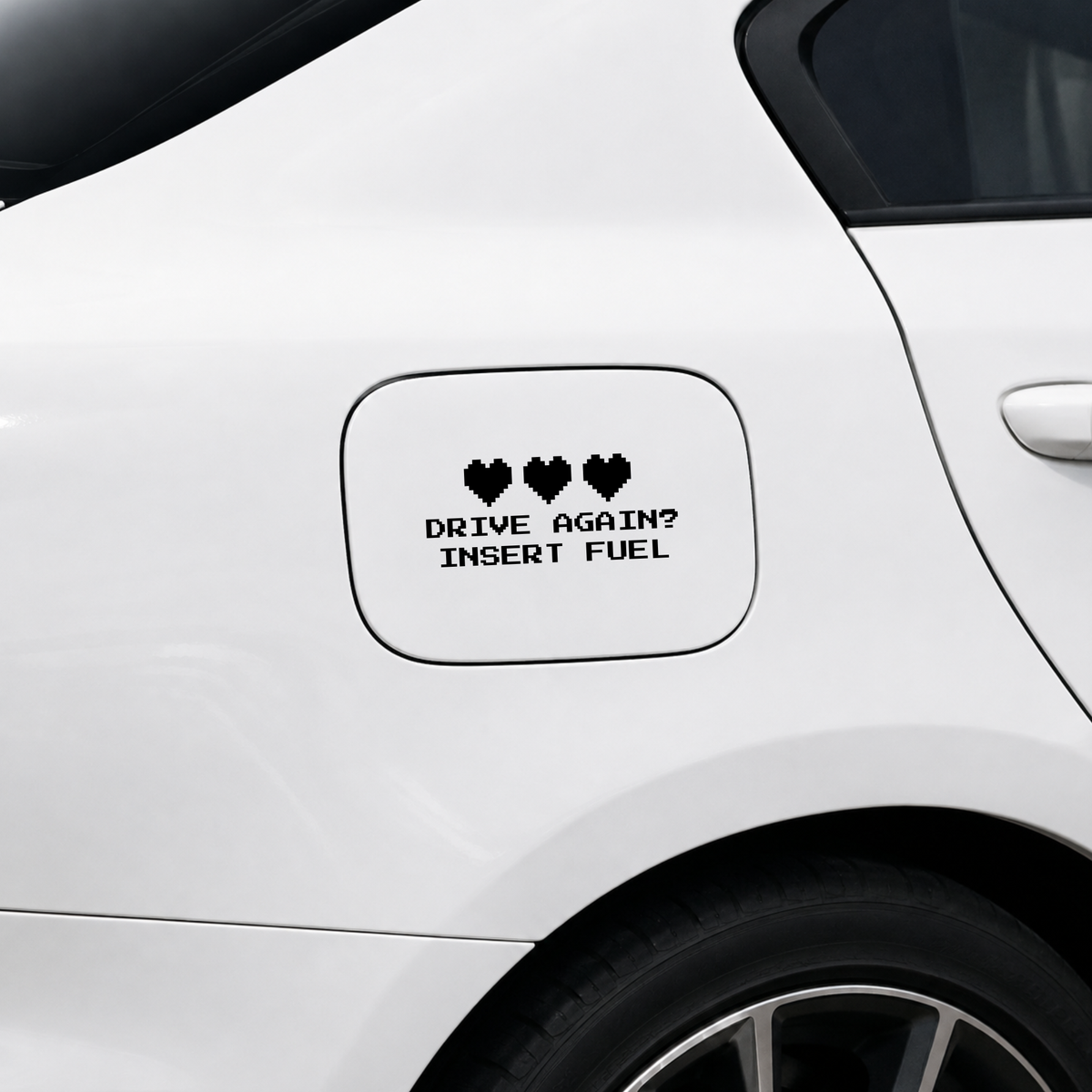A black vinyl decal with three hearts and the text 'DRIVE AGAIN? INSERT FUEL' applied to the fuel door of a white car.