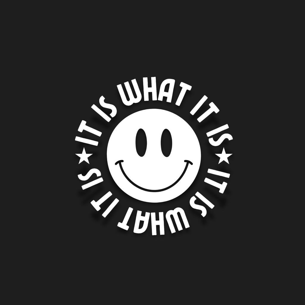 A white circular sticker or decal featuring a simple smiley face in the center with the phrase 'IT IS WHAT IT IS' written around it in a bold, curved font, set against a solid black background.