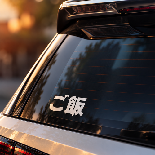A white vinyl decal with Japanese characters 'に本' on the rear window of a silver SUV, photographed in warm golden hour sunlight.